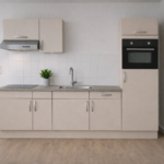 Moderne rechte keuken in cashmere kleur met ingebouwde oven, afzuigkap en spoelbak, geplaatst tegen een muur met patroonbehang en sfeerverlichting