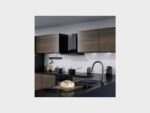 "Moderne keuken met houtlook kastfronten, zwarte werkbladen, zwarte wandafzuigkap, inbouwoven en chromen keukenkraan. Op het aanrecht liggen een vers brood en een broodmes, en de achterwand is afgewerkt met een lichte marmerlook